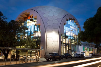 Modern domed building with hexagonal patterns and glass walls at night.