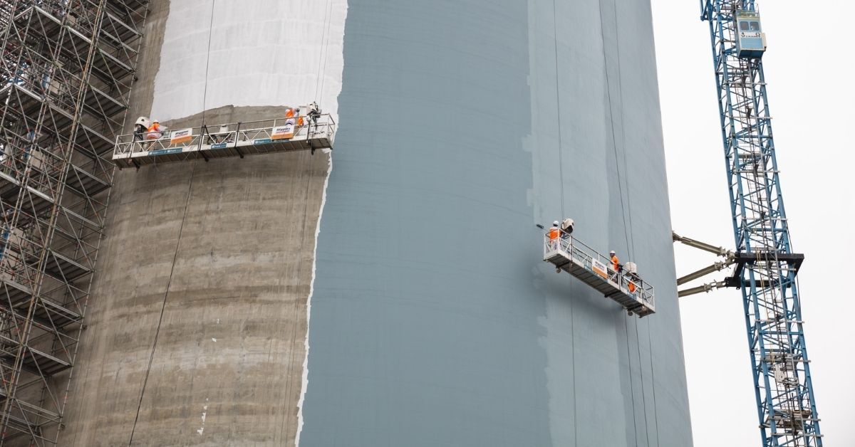 A professional Higgins painting team on scaffolding providing building maintenance services.